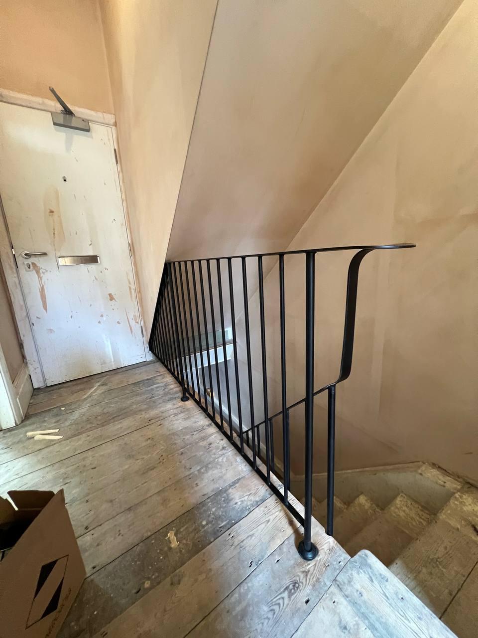 Black metal landing balustrade with a curved handrail end in a London property under renovation