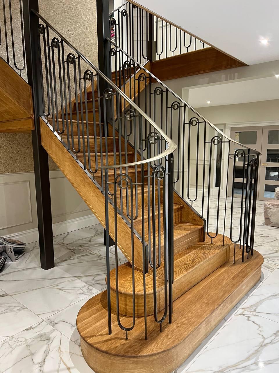 Decorative black staircase balustrade with looped verticals and a polished curved handrail