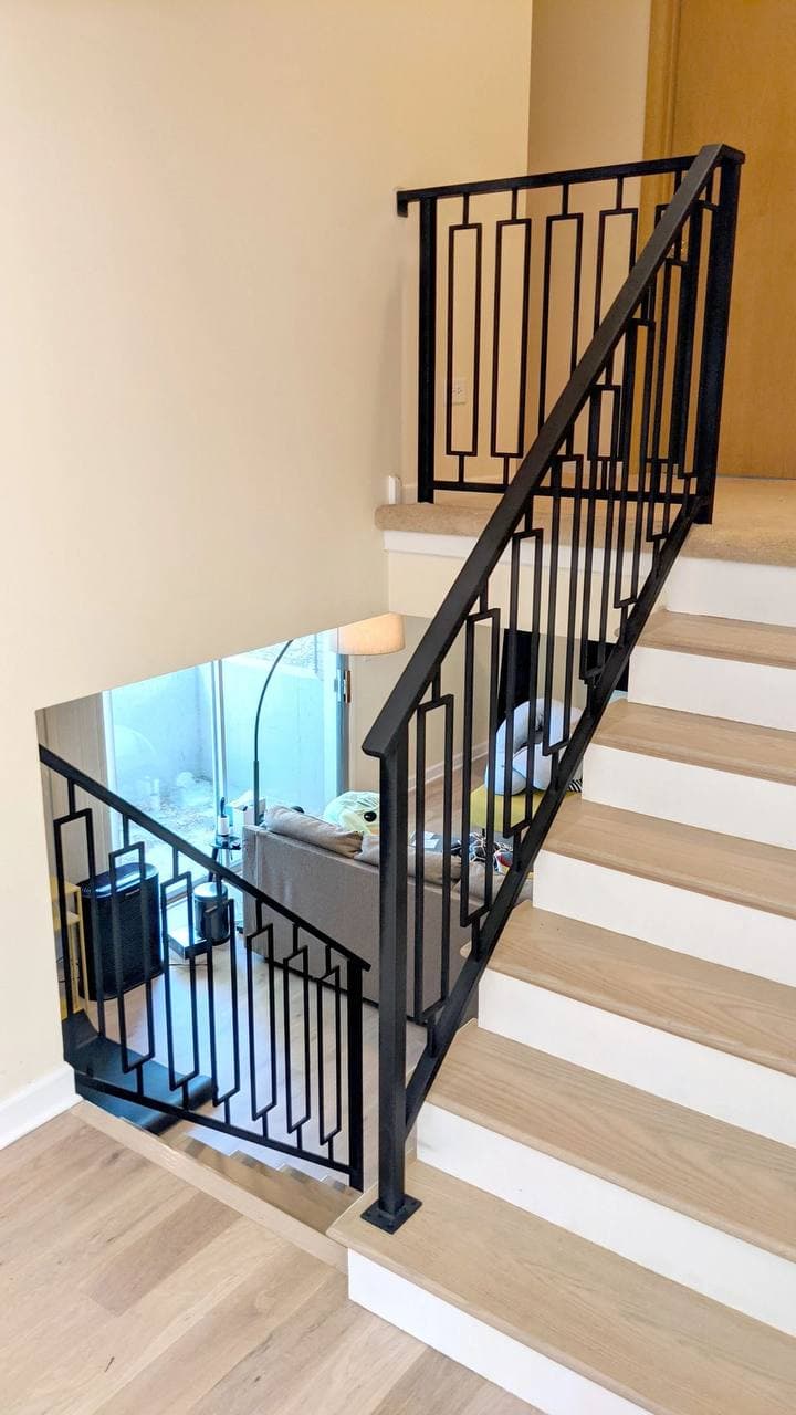 Black geometric metal balustrade installed around a light timber staircase