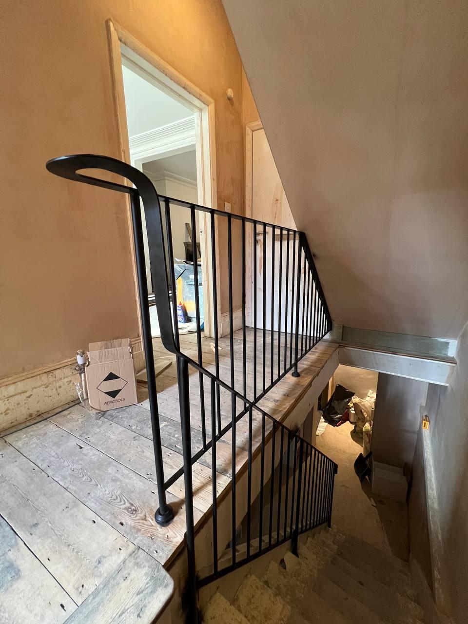 Curved landing balustrade viewed across the stairwell during renovation