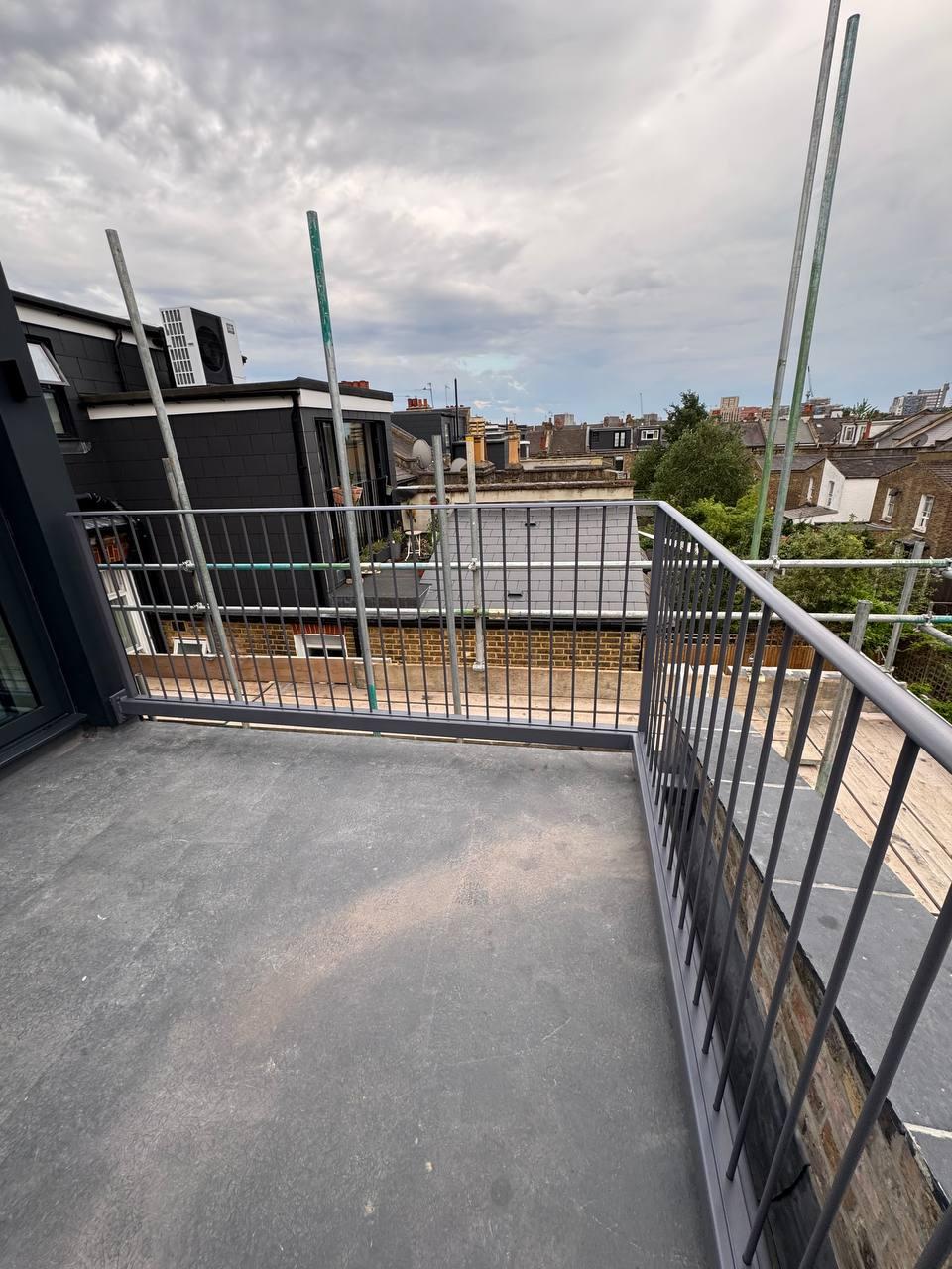 Dark-grey metal rooftop railings fitted along the terrace edge and adjoining brick parapet.