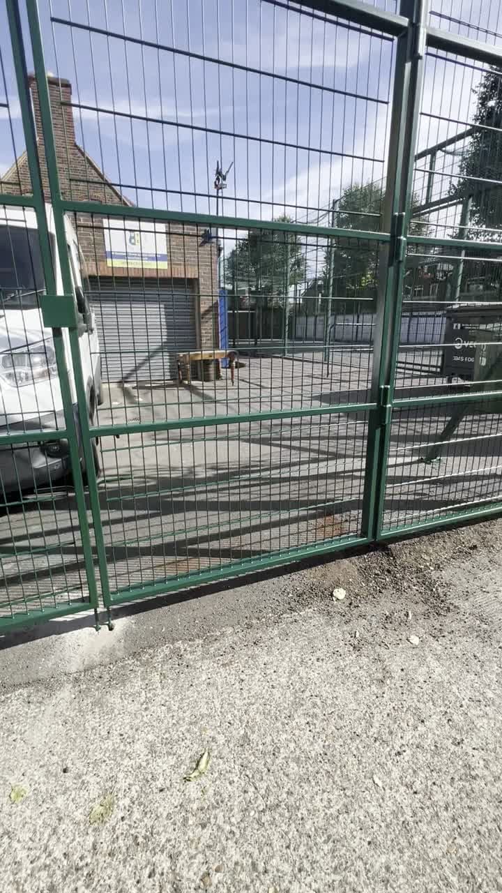Close view of the installed green mesh bifold gate panels and their movement at the entrance