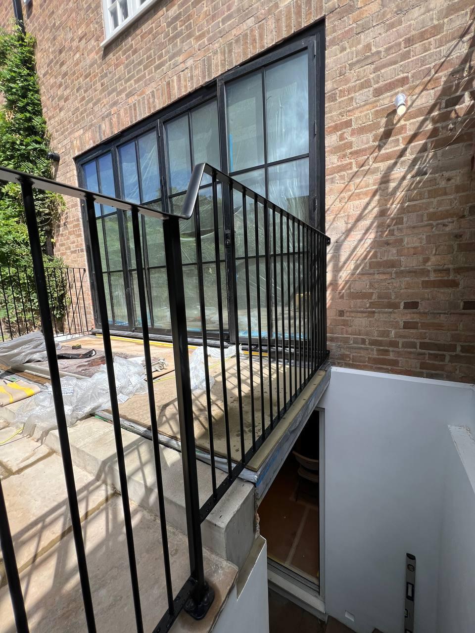 Exterior black balustrade enclosing the stair opening beside glazed doors