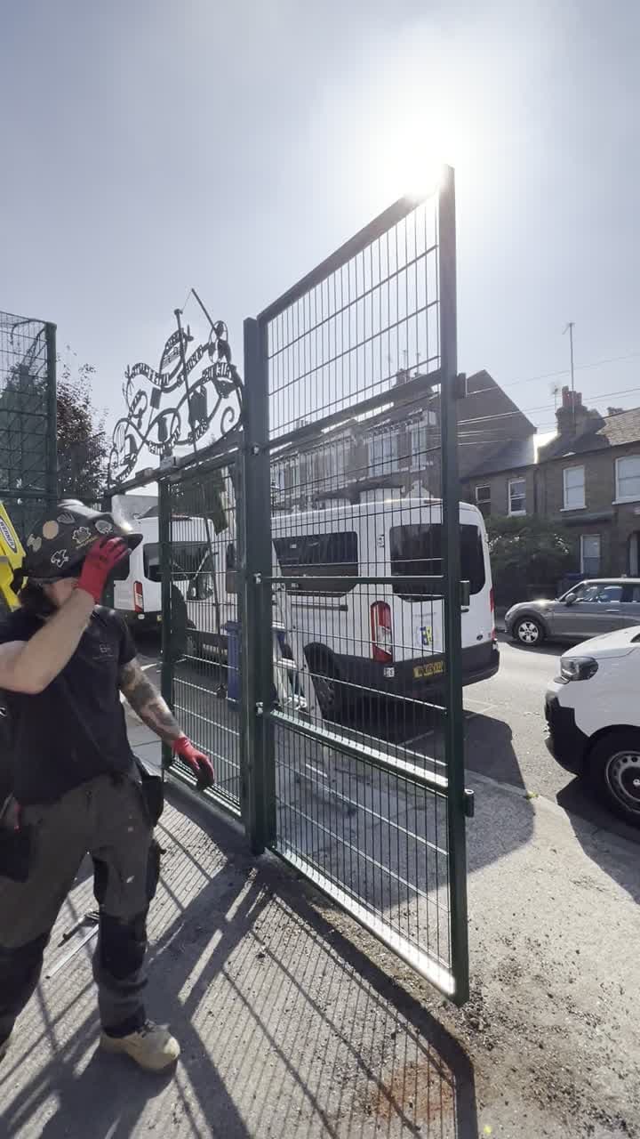 Black Heath Metalworks team member opening a finished green gate leaf at the youth club entrance