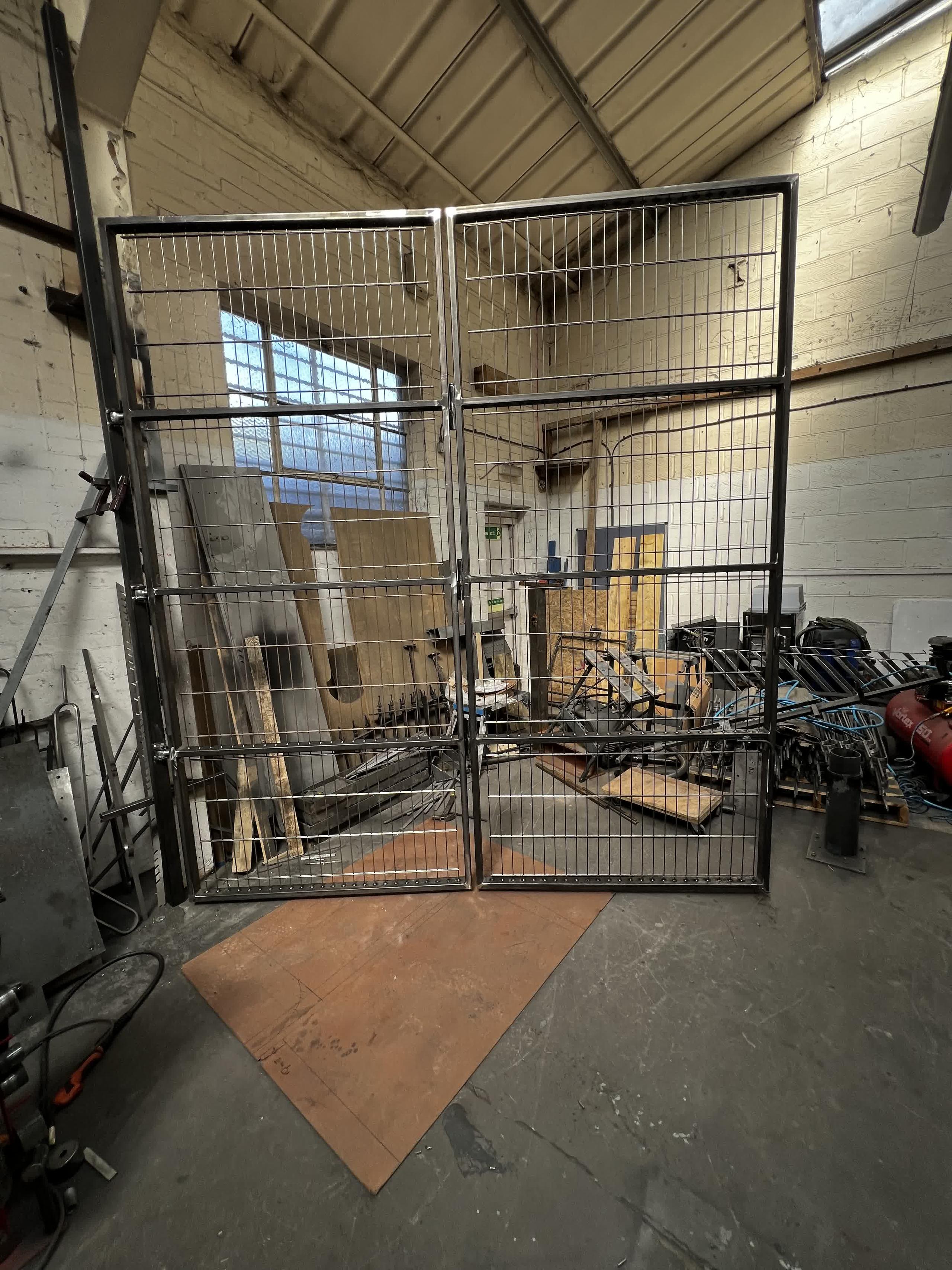 Front view of the unfinished four-leaf welded mesh bifold gate standing open in the workshop