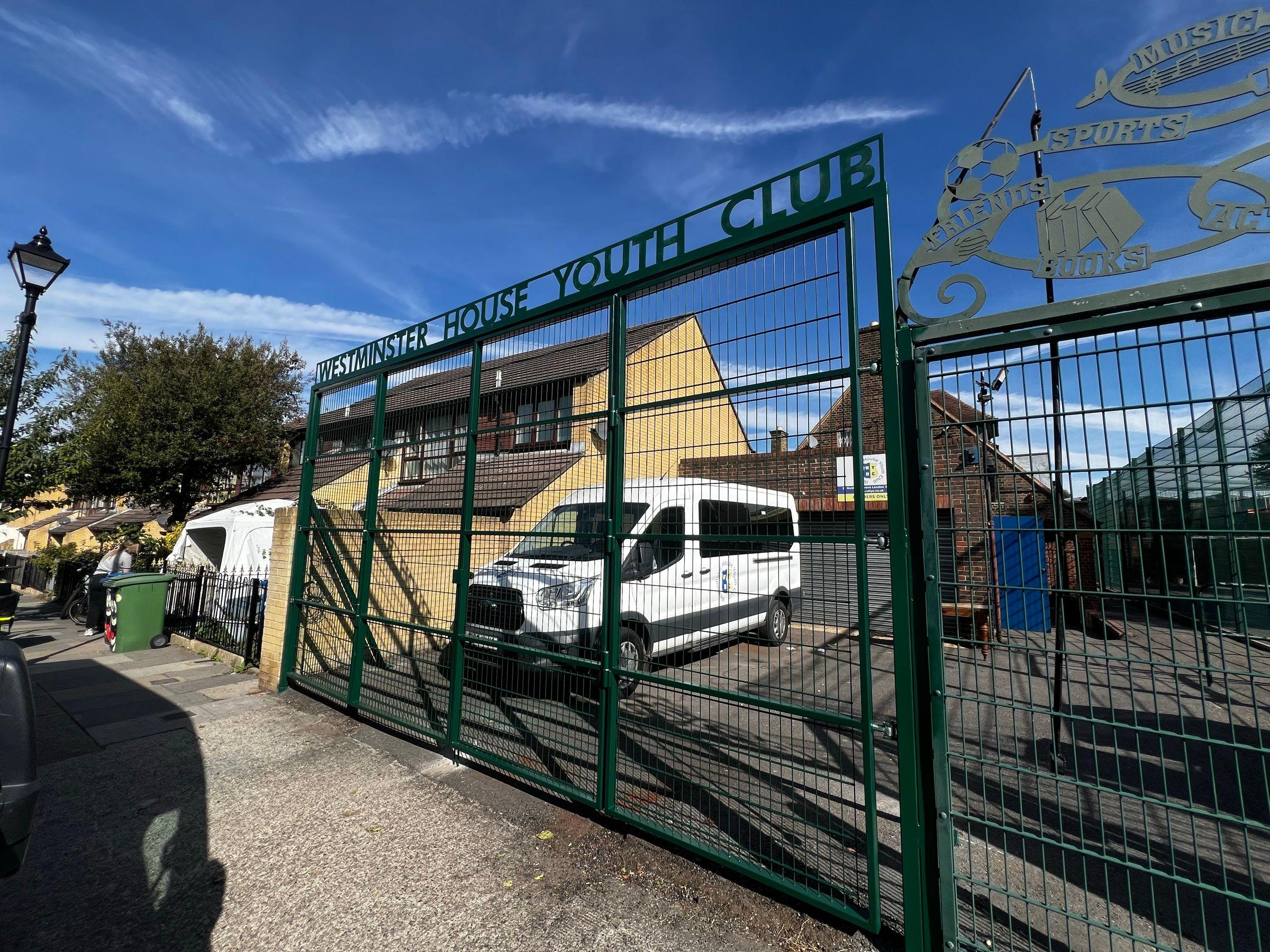 Finished green mesh bifold driveway gates viewed from the side at Westminster House Youth Club
