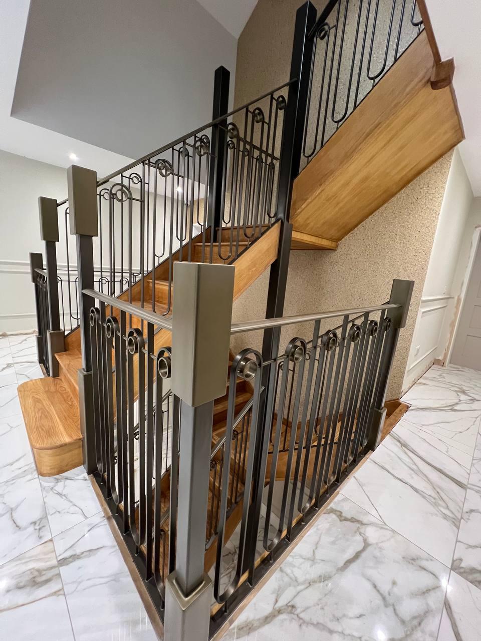 Decorative black landing balustrade with looped details, square posts and a polished handrail
