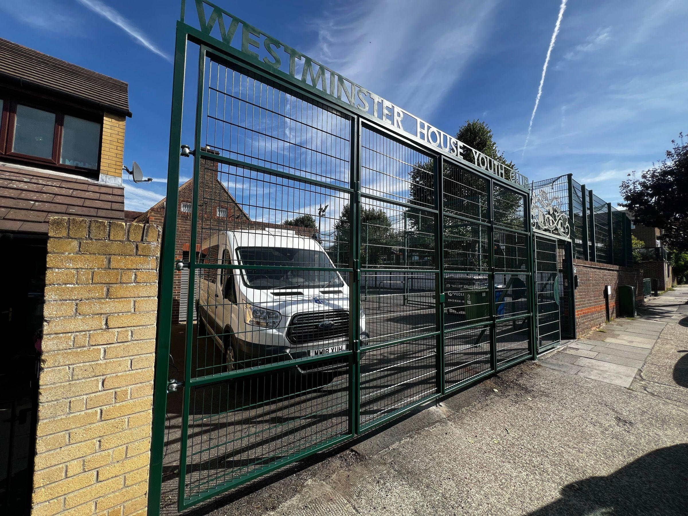 Finished green four-leaf bifold driveway gates across the youth club entrance