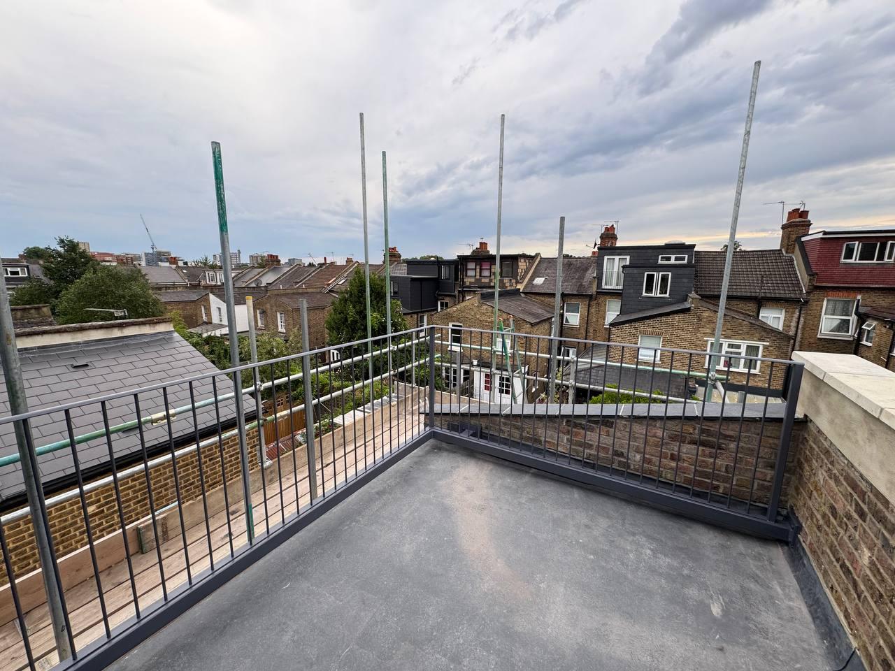 Rooftop terrace enclosed by grey vertical-bar railings viewed from inside the terrace
