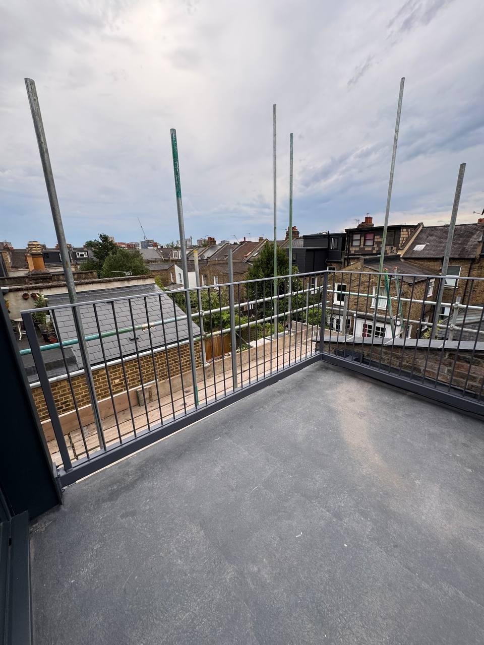 Wide view of vertical-bar metal railings enclosing the corner of a London rooftop terrace.